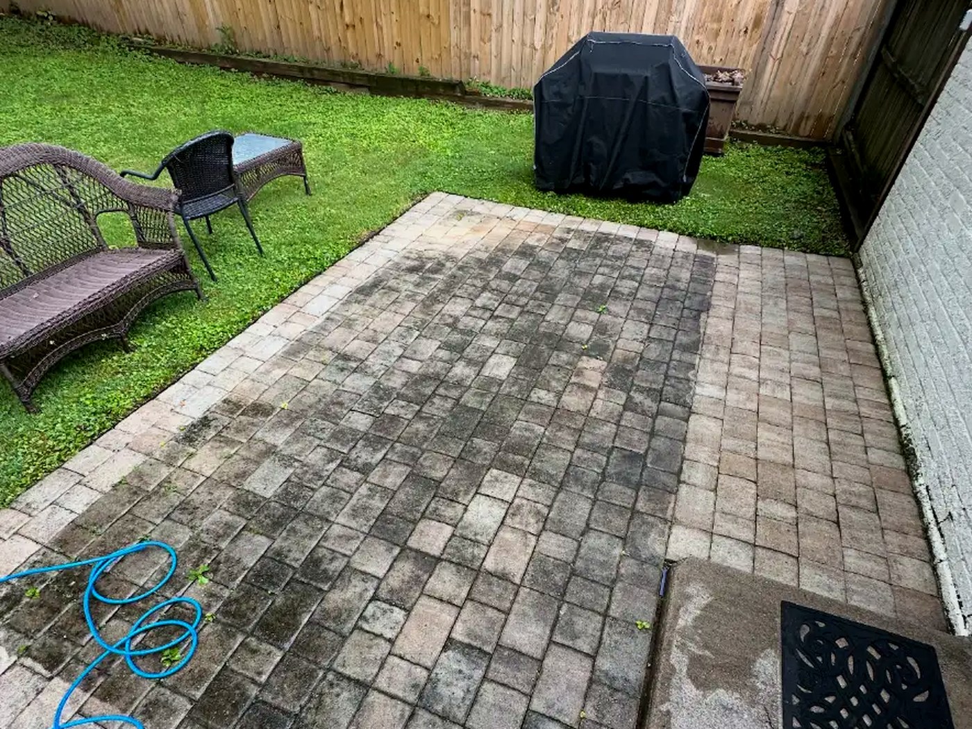 Paver patio darkened by algae and grime before cleaning