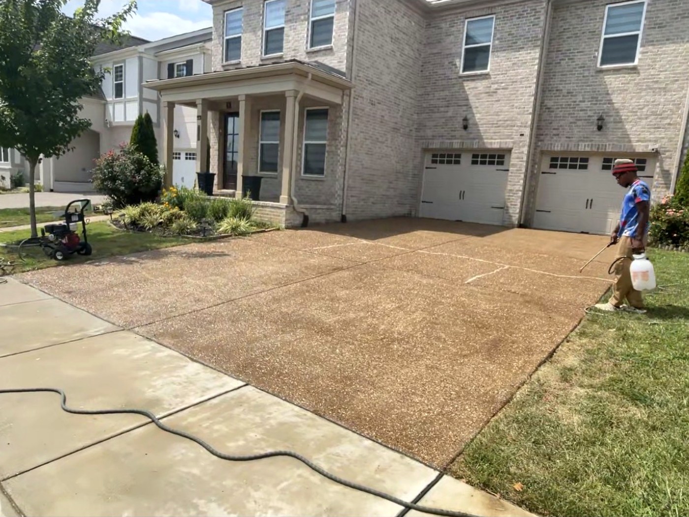 Sealer being applied to an exposed-aggregate driveway, restoring its color